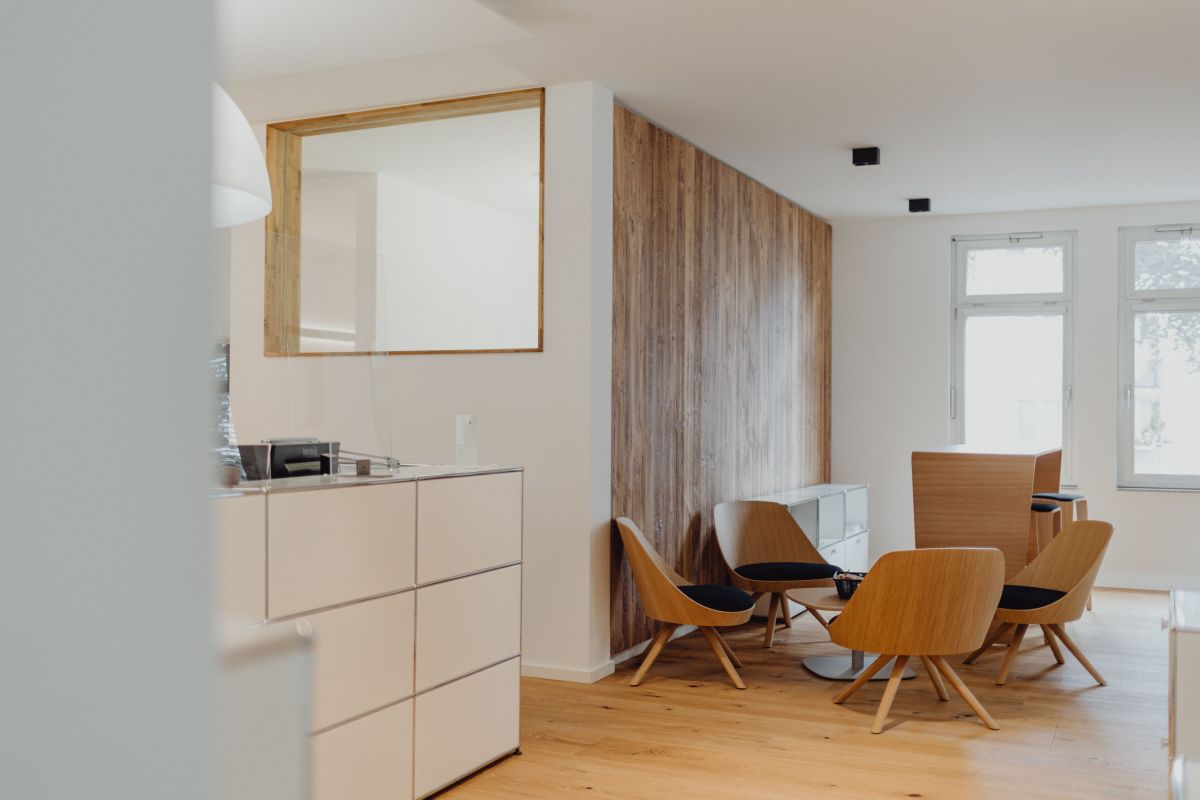 Moderner Empfangs- und Wartebereich mit Designmöbeln, Holzdetails und natürlichem Licht für stilvolles, professionelles Ambiente.