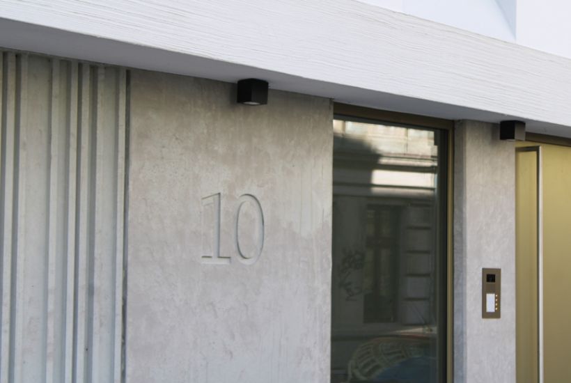 Moderner Eingangsbereich mit Betonelementen, integrierter Hausnummer 10 und hochwertigem Zugangssystem.