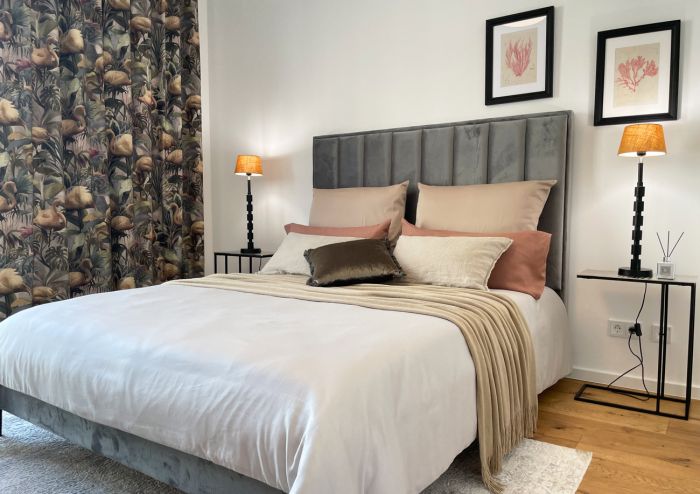 Stilvoll eingerichtetes Schlafzimmer mit Designerbett, Naturholzparkett und luxuriösen Textilien in elegantem Ambiente.