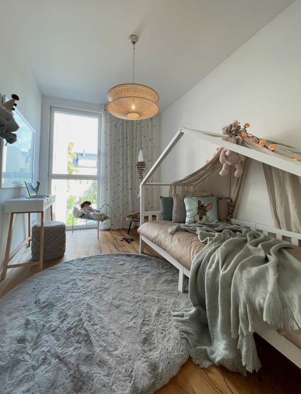 Lichtdurchflutetes Kinderzimmer mit verspieltem Bett, Naturholzfußboden und gemütlichem Wohnambiente.