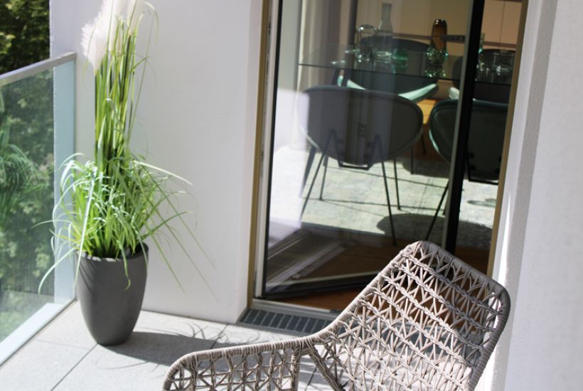 Privater Balkon mit stilvoller Möblierung und Glasbrüstung – entspannter Rückzugsort mit Blick ins Grüne.