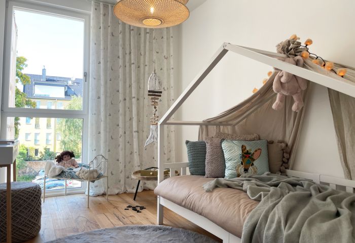 Lichtdurchflutetes Kinderzimmer mit liebevoller Einrichtung, bodentiefem Fenster und wohnlichem Eichenparkett.
